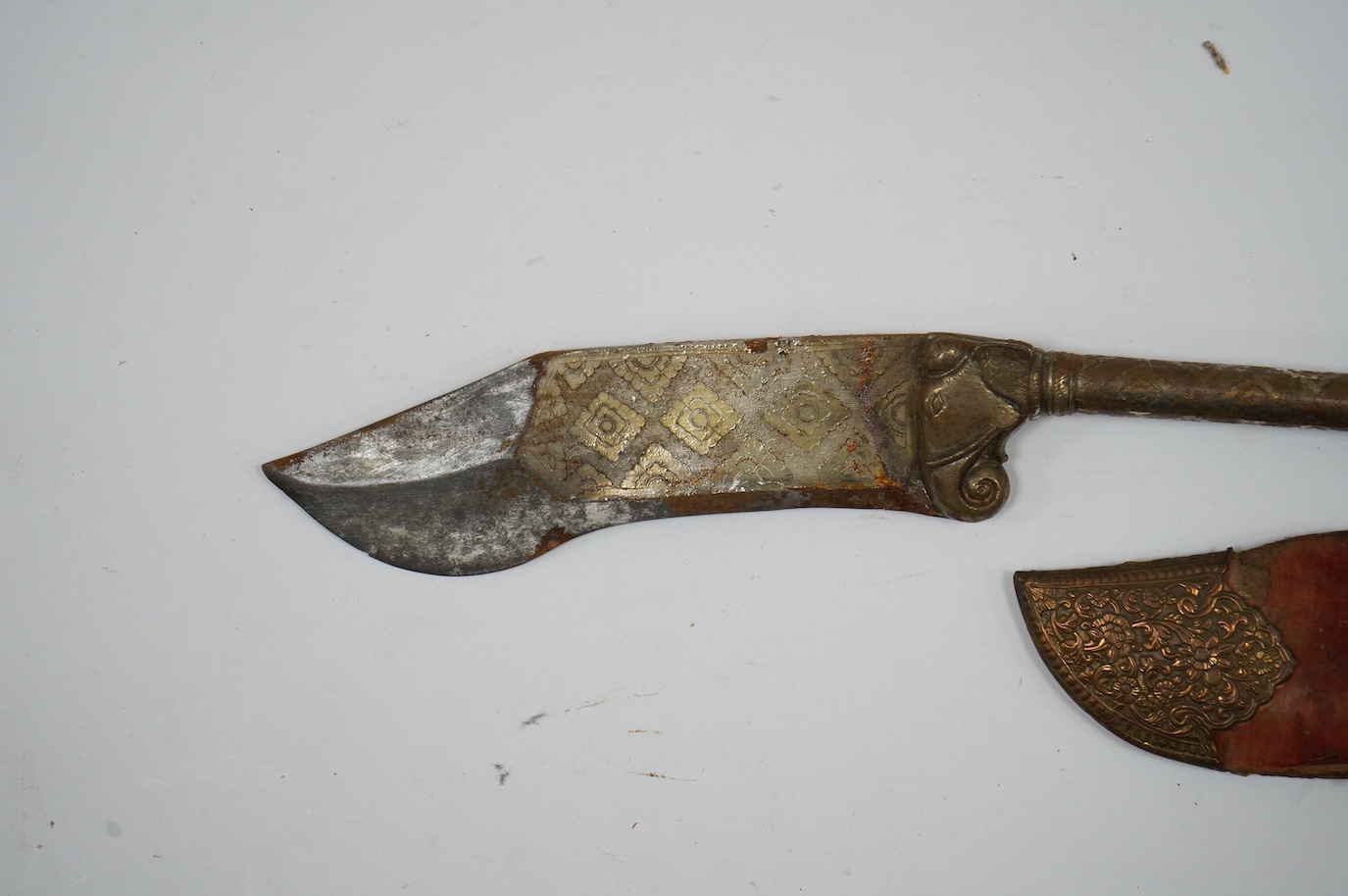 An Indian axe bhuj, with broad curved blade, iron haft with elephant head top, all covered over with silver gilt foil engraved with flower heads, the pommel unscrews to reveal a stiletto, with its copper mounted sheath,